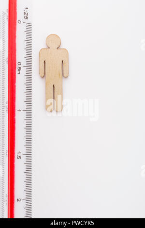 Makro kleine Laser-cut Holzfigur und Lineal. Metapher Messen persönliche Leistung, Demographie Konzept, Produktivität, die Maßnahme von einem Mann bekommen. Stockfoto