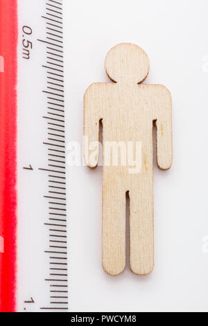 Makro kleine Laser-cut Holzfigur und Lineal. Metapher Messen persönliche Leistung, Demographie Konzept, Produktivität, die Maßnahme von einem Mann bekommen. Stockfoto
