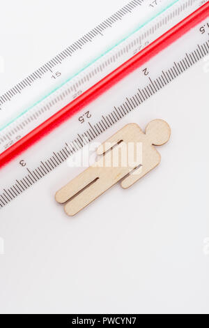 Makro kleine Laser-cut Holzfigur und Lineal. Metapher Messen persönliche Leistung, Demographie Konzept, Produktivität, die Maßnahme von einem Mann bekommen. Stockfoto