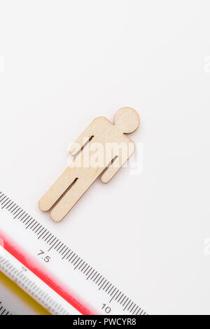Makro kleine Laser-cut Holzfigur und Lineal. Metapher Messen persönliche Leistung, Demographie Konzept, Produktivität, die Maßnahme von einem Mann bekommen. Stockfoto