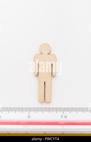 Makro kleine Laser-cut Holzfigur und Lineal. Metapher Messen persönliche Leistung, Demographie Konzept, Produktivität, die Maßnahme von einem Mann bekommen. Stockfoto