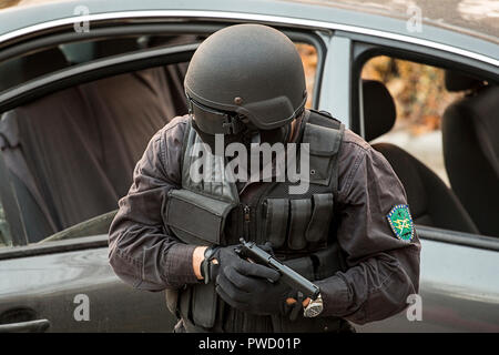 Eine bewaffnete und maskierte spezielle Einheiten überprüft ein Fahrzeug. Stockfoto