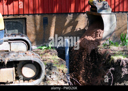 Bagger in Baustelle füllen das kanalrohr Graben mit Sand. Stockfoto