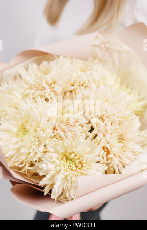 Üppigen Bouquet von seltenen Chrysantheme. Junge Mädchen, dass eine Blumen Arrangements mit verschiedenen Farben. weiße Wand. Stockfoto