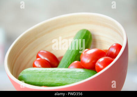 Mini Tomaten mit Mini Gurken in eine hölzerne Schüssel. Sanfte Farben, perfekt für ein Restaurant oder Diner. Gemüse in eine Schüssel geben, Gesundheit Nahrung. Stockfoto