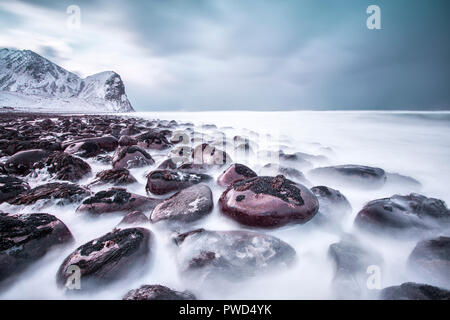 Felsen am Strand durch den Wind modelliert umgeben das eisige Meer Unstad Lofoten norwegen Europa Stockfoto