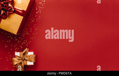 Verschiedene Geschenkboxen mit kleinen goldenen Sternen auf rotem Hintergrund. Ansicht von oben Weihnachtsgeschenke mit Sternen. Flach kopieren Komposition mit viel Platz. Stockfoto