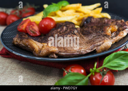 Saftiges steak Rindfleisch mit Tomaten und Pommes Frites Stockfoto