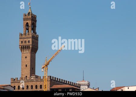 Der Turm des Palazzo Vecchio gegen einen strahlend blauen Sommerhimmel mit einem baukran im Vordergrund. Stockfoto