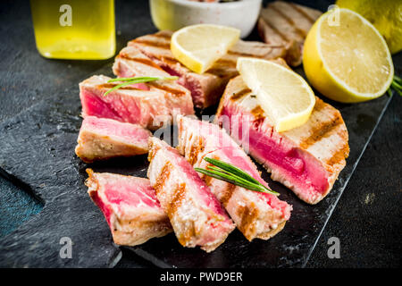 Gegrillter Thunfisch Fisch Steaks mit Zitrone und Gewürze, Dunkelblau konkreten Hintergrund Kopie Raum, Ansicht von oben Stockfoto