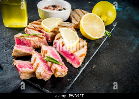 Gegrillter Thunfisch Fisch Steaks mit Zitrone und Gewürze, Dunkelblau konkreten Hintergrund Kopie Raum, Ansicht von oben Stockfoto