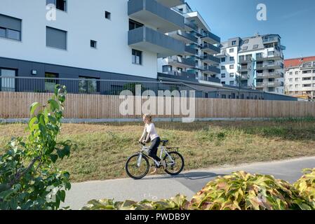 Wien, Eine Radfahrerin der modernen Wohnhausanlage Schiffmühlenstraße 120 - Wien, moderne Apartment House Stockfoto