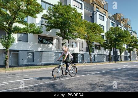 Wien, Eine Radfahrerin der modernen Wohnhausanlage Schiffmühlenstraße 120 - Wien, moderne Apartment House Stockfoto