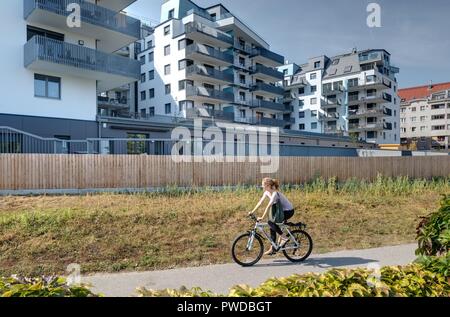 Wien, Eine Radfahrerin der modernen Wohnhausanlage Schiffmühlenstraße 120 - Wien, moderne Apartment House Stockfoto