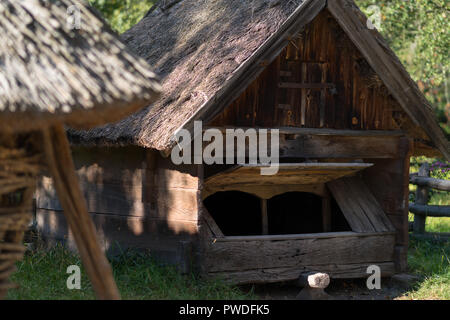 Rustikale verwitterten strohgedeckten Holzhütte oder Kabine unter grünen Bäumen in der Nähe zu sehen. Stockfoto