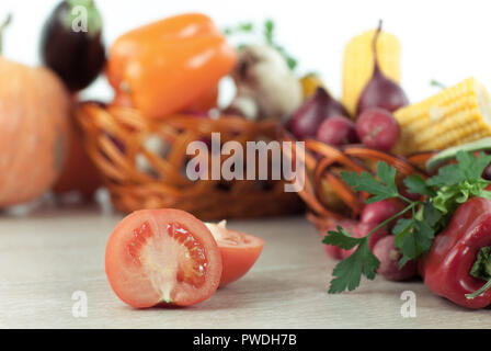 Frisches Gemüse in Weidenkörbe auf dem Holztisch. Stockfoto