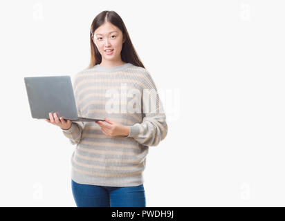 Junge chinesische Frau über isolierte Hintergrund über Computer Laptop mit einem glücklichen Gesicht stehen und lächelnd mit einem selbstbewussten lächeln zähne Stockfoto