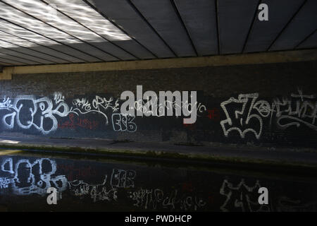 Am Kanal gelegenes Graffiti an der Unterseite der Brücke, die über den Birmingham Ladywood Mittelweg den Kanal refelcted in die noch Wasser des Kanals Stockfoto