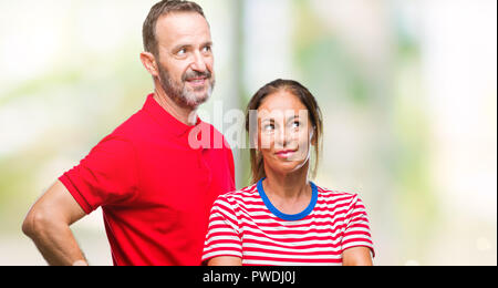 Mittleres Alter spanischer Paar in Liebe über isolierte Hintergrund lächelnd Seite suchen und sie starrte Denken. Stockfoto