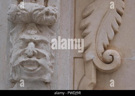 Dekorative Gesicht und Emblem Schnitzereien an der Kirchenmauer in Ciutadella Menorca Spanien Stockfoto