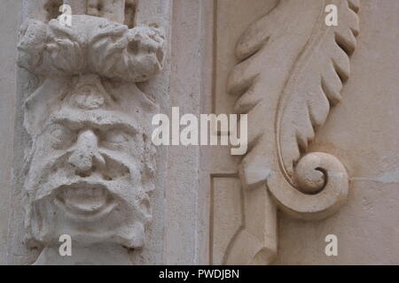 Dekorative Gesicht und Emblem Schnitzereien an der Kirchenmauer in Ciutadella Menorca Spanien Stockfoto