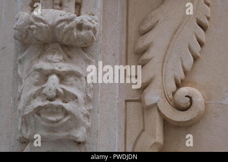 Dekorative Gesicht und Emblem Schnitzereien an der Kirchenmauer in Ciutadella Menorca Spanien Stockfoto