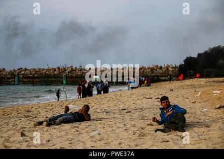 Gaza, Palästina. 15. Oktober 2018. Palästinensische Jugendliche auf den am Boden Liegenden nach Gas Einatmen während Demonstrationen zwischen Palästinensern und der israelischen Armee in den nördlichen Gazastreifen in der Nähe von Zakim reißen. Palästinenser protestieren seit März 30th, 2018 Aufruf zum Ende des israelisch Blockade von Gaza, das Recht der Palästinenser auf ihr angestammtes Land zurückzukehren, sowie gegen die Entscheidung von Trump Jerusalem als Hauptstadt Israels zu erkennen. Credit: SOPA Images Limited/Alamy leben Nachrichten Stockfoto