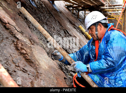 (181016) - Peking, 16. Okt., 2018 (Xinhua) - Nikoeaos Salamparchos, ein Experte aus dem Geopark Lesbos in Griechenland, arbeitet während einer Dinosaur footprint Erhaltung Projekt an der Yanqing globale Geopark Yanqing Bezirk von Peking, der Hauptstadt von China, 15. Oktober 2018. Fachleute aus China und Griechenland haben gemeinsame Konservierungsarbeiten auf versteinerte Fußabdrücke von Dinosauriern in Yangqing begann sie von Wetter, um Beschädigungen zu vermeiden. Die Abdrücke sind vermutlich durch die Dinosaurier vor 150 Millionen Jahren gelassen zu werden. (Xinhua / xiaoguang Luo) (Gni) Stockfoto