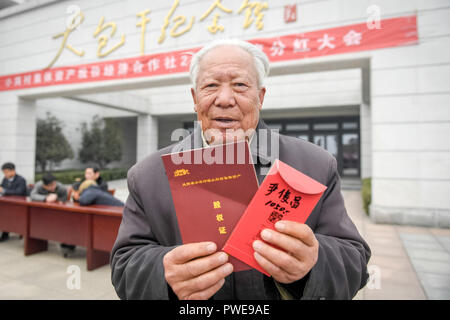 (181016) - FENGYANG, Oktober 16, 2018 (Xinhua) - Yan Junchang, einem führenden Dorfbewohner dann die geheime Vereinbarung zu Teilen zu unterzeichnen gemeinschaftlich Ackerland in Familie Grundstücke im Jahr 1978 besaß, zeigt die Dividende aus dem Dorf kollektiven Wirtschaft Ergebnis auf Xiaogang Dorf in Fengyang Grafschaft empfing, im Osten der chinesischen Provinz Anhui, Feb 9, 2018. Xiaogang ist in Fengyang (Phoenix) Grafschaft. Die Grafschaft, wie seine mythologischen Namensvetter, hat durch Hunderte von reinkarnationen im Laufe der Jahrhunderte gegangen, wie Gemeinschaften wie Xiaogang Schlacht eine unbeständige Umgebung, um genügend Nahrung zu überleben Eke. 1978, 18 Bauern kamen tog Stockfoto