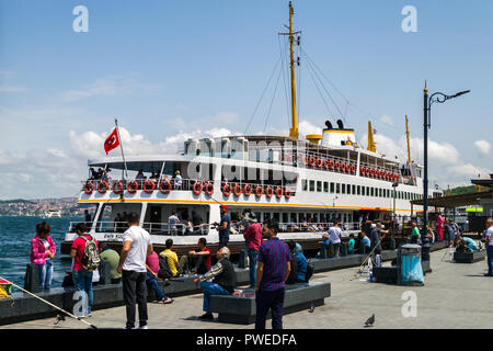 Man saß auf Stein sitzen von Eminonu Pier mit Fähre im Hintergrund angedockt, Istanbul, Türkei Stockfoto