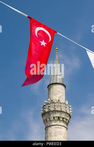 Eine rote Türkische Flagge vor einem Minarett einer Moschee an einem sonnigen Tag, Istanbul, Türkei Stockfoto