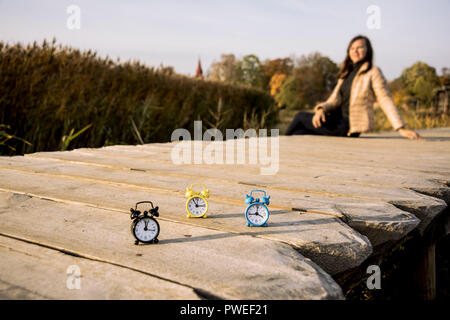 Drei kleine Alarm retro Uhren auf Holz- Oberfläche. Herbst abstrakten Foto. Sommerzeit. Stockfoto