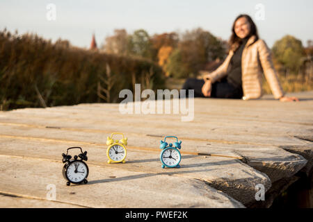Drei kleine Alarm retro Uhren auf Holz- Oberfläche. Herbst abstrakten Foto. Sommerzeit. Stockfoto