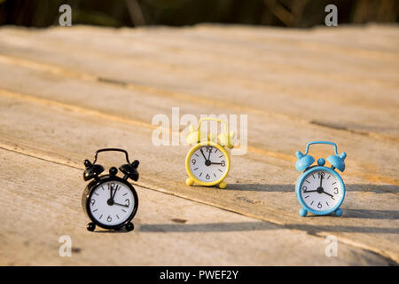 Drei kleine Alarm retro Uhren auf Holz- Oberfläche. Herbst abstrakten Foto. Sommerzeit. Stockfoto