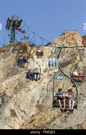 Sessellift. Menschen mit spektakulärem Blick über Alum Bay und den Strand. Isle of Wight. Atemberaubende Fahrten zum Strand hinunter und dann wieder ein. Stockfoto