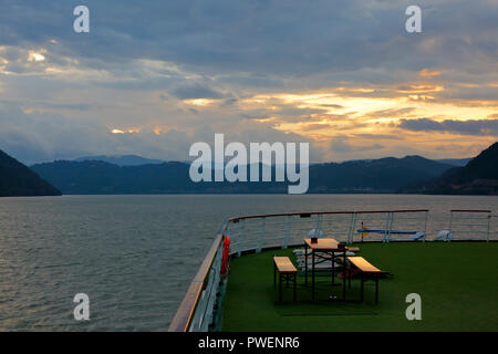 Serbien, Rumänien Südkarpaten, Serbische Karpaten, Banat Berge, Djerdap Nationalpark, Katarakte, Eisen Tore, Donau Water Gap, Flusskreuzfahrt auf der Donau, Donau Navigation, aROSA 393 Mia, Flusslandschaft, Donau Landschaft, Berge, bergige Landschaften, steilen Felsen, Abend, Sonnenuntergang, dunkle Wolken Stockfoto