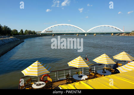 Serbien, in Novi Sad an der Donau, Provinz Vojvodina, Bezirk Süd Backa, Flusskreuzfahrt auf der Donau, Ausflug Schiff, offenen Achterdeck auf dem Cruiser aROSA Mia, Sonnenschirme, Tourismus, Donau Navigation, Blick auf zwei Donaubrücken, Straßen-, Brücken- und Eisenbahnbrücken, hinter der Brücke, die meisten Zezeljev Zezelj, vor der Brücke, Bosko Perosevic Road-Railway Brücke, Die meisten boska Perosevica, der Europäischen Kulturhauptstadt 2021 Stockfoto