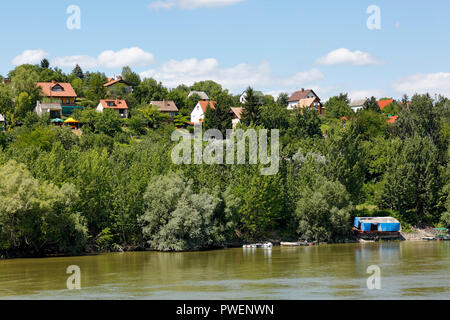 Ungarn, Mohacs auf der Donau, Transdanubien, Südtransdanubien, Komitat Baranya, Wohnhäuser auf einem Hügel über der Donau, Einfamilienhäuser, Ufer, Landschaft, Bäume und Büsche am Ufer der Donau, cumulus Wolken Stockfoto