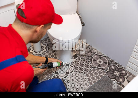 Klempner Anwendung tragen Sie Silikondichtmittel um Wasser Schrank Stockfoto