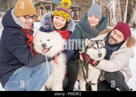 Porträt von zwei Glückliche Paare spielen mit schönen Hunde im Freien und genießen Sie die Zeit im Winter Resort Stockfoto