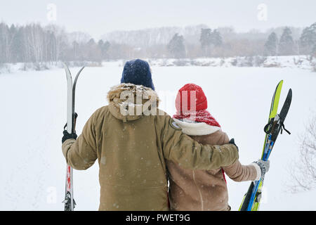 Zurück Portrait von liebevolle junge Paare auf der Suche nach Ansehen der schönen Winterlandschaft während der Pause beim Skifahren Reise anzeigen, kopieren Raum Stockfoto