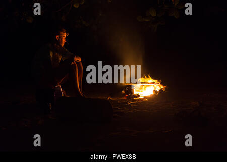 Bild von einem großen Lagerfeuer, um das die Menschen in die Berge bei Nacht sonnt Stockfoto