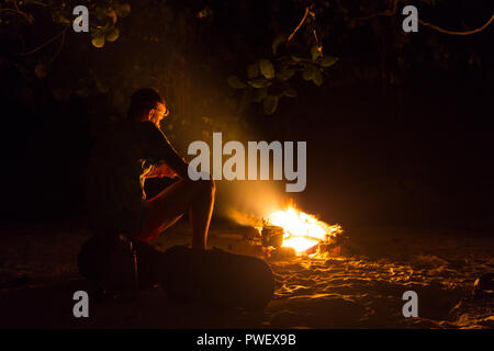 Bild von einem großen Lagerfeuer, um das die Menschen in die Berge bei Nacht sonnt Stockfoto