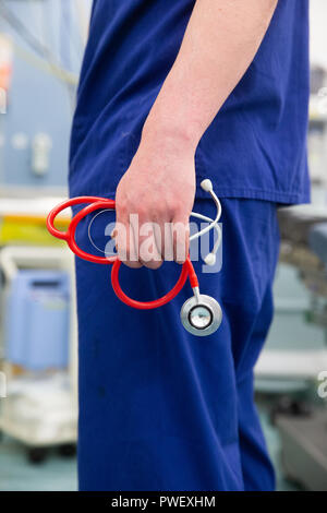 Nahaufnahme der Hand eines NHS Arzt mit einem Stethoskop in einem Krankenhaus Theater Stockfoto