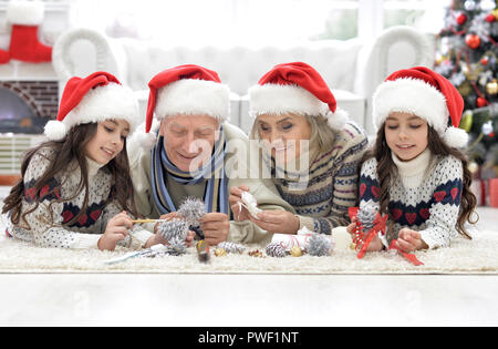 Porträt von glücklichen Großeltern mit Zwillingsmädchen, die Vorbereitungen für Weihnachten zu Hause Stockfoto