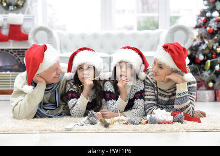 Porträt von glücklichen Großeltern mit Zwillingsmädchen, die Vorbereitungen für Weihnachten zu Hause Stockfoto