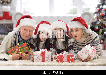 Portrait von glücklichen Großeltern mit 2 Mädchen Weihnachten zu Hause feiern. Stockfoto