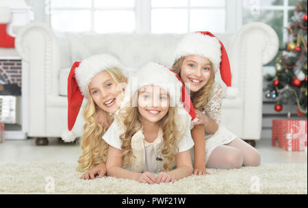 Portrait von drei süße kleine Mädchen in Santa Hüte auf dem Boden liegend Stockfoto