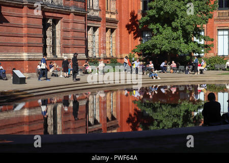 Bunte Reflexionen von Menschen und Gebäuden in den Pool in der John madejski Garten an der V&A Museum in London, Großbritannien, an einem warmen, sonnigen Tag im September. Stockfoto