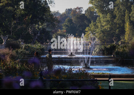 Sonne funkeln auf zwei Brunnen in Pools im Italienischen Garten in Kensington Gardens, London, UK im Herbst. Üppige Vegetation umgibt die ruhigen Gegend Stockfoto